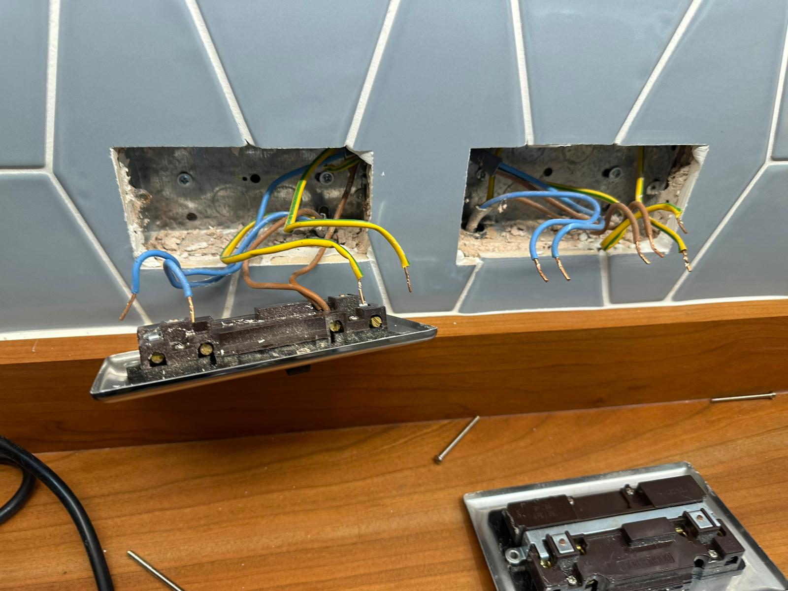 Two sockets removed from the wall showing the wiring behind, ready for replacement